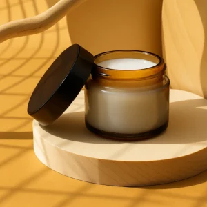 Amber glass jar containing 30 ml of organic castor oil infused with pearl powder, giving the oil a soft milky-white glow. The jar sits elegantly on a wooden pedestal surrounded by scattered pearl powder and loose pearls, evoking purity, beauty, and natural luxury.