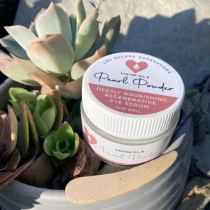 Pearl powder infused castor oil eye serum jar with lid beside succulents and wooden spatula, natural pearl powder eye serum product photo