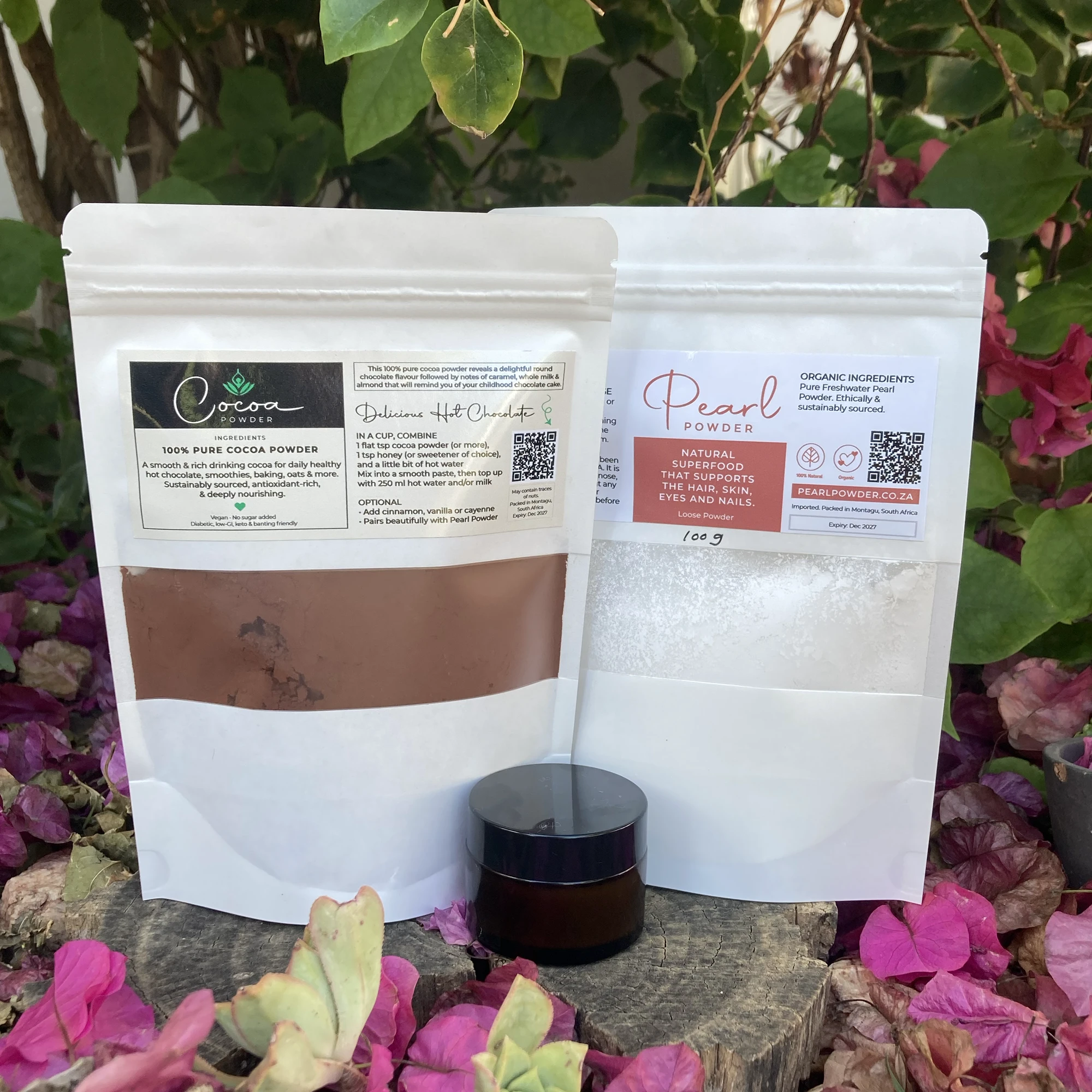 Pearl powder and cocoa powder with castor oil pearl eye serum — natural beauty ritual bundle photographed in a garden setting.